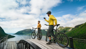 Image of a couple taking photos while enjoying a scenic cycling vacation in Norway