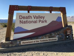Sign marking the entrance to Death Valley National Park, California, with mountains in the background
