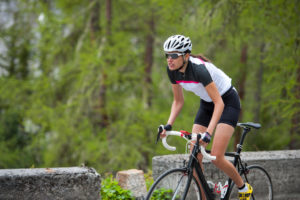 cycling climbing tip about how to ride uphill standing on the pedals – Woman cycling up a hill with good out of the saddle technique
