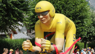 photo of a motorized float in the tour de france caravan, featuring an effigy of the race leader in yellow jersey