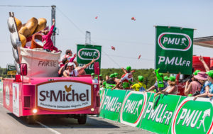 photo of a motorized float in the tour de france caravan, with free packages of biscuits being thrown to an enthusiastic crowd