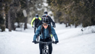A woman cycling along snowy mountain bike trails in winter