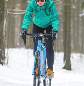 Woman cycling on trails in winter on a gravel bike.