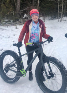 Cam wears Terry and poses with her rented fat bike on a snowy trailhead
