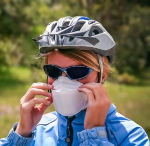 A cyclist adjusting her face mask ready for cycling