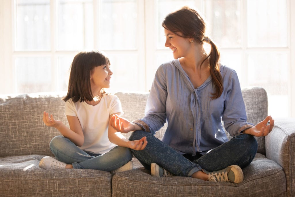 Mom and daughter share a laugh while practicing mindfulness on the couch