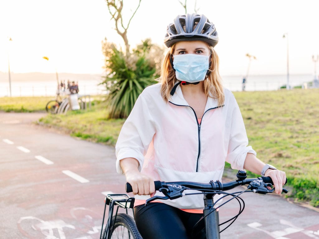 Woman paused during bike ride, wearing face mask during covid-19 pandemic