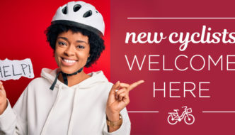 woman in cycling helmet with hand made sign reading help, and text overlayed reading new cyclists welcome here