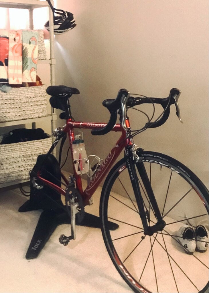 Lisa's indoor cycling setup, with bike on stationery stand in her office, and shelves of bike gear near at hand