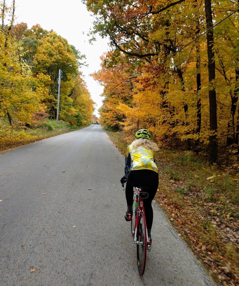 Tracy Flucke rides along a lane lined with fall foliage
