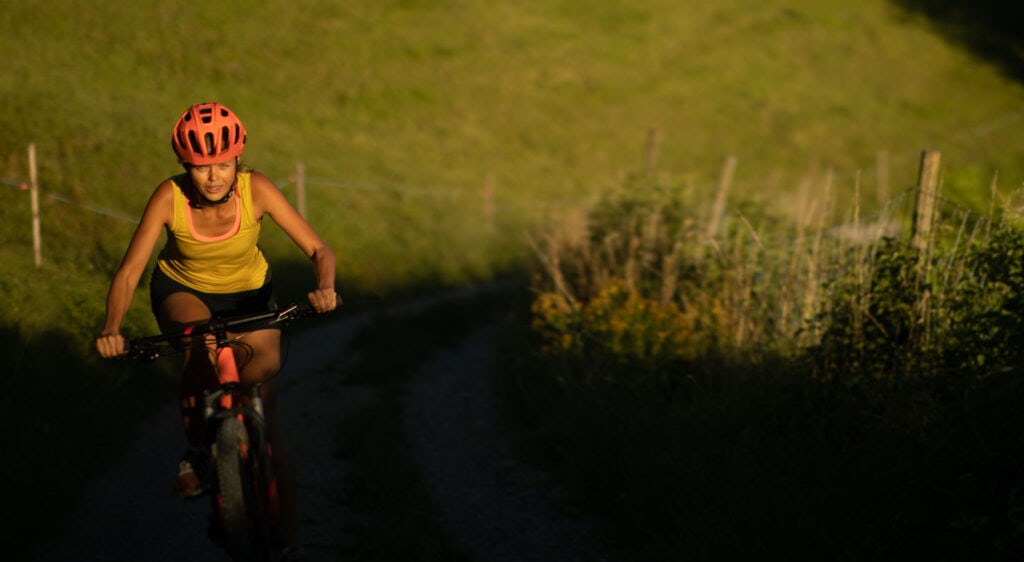 Woman riding uphill in countryside in sunset lighting