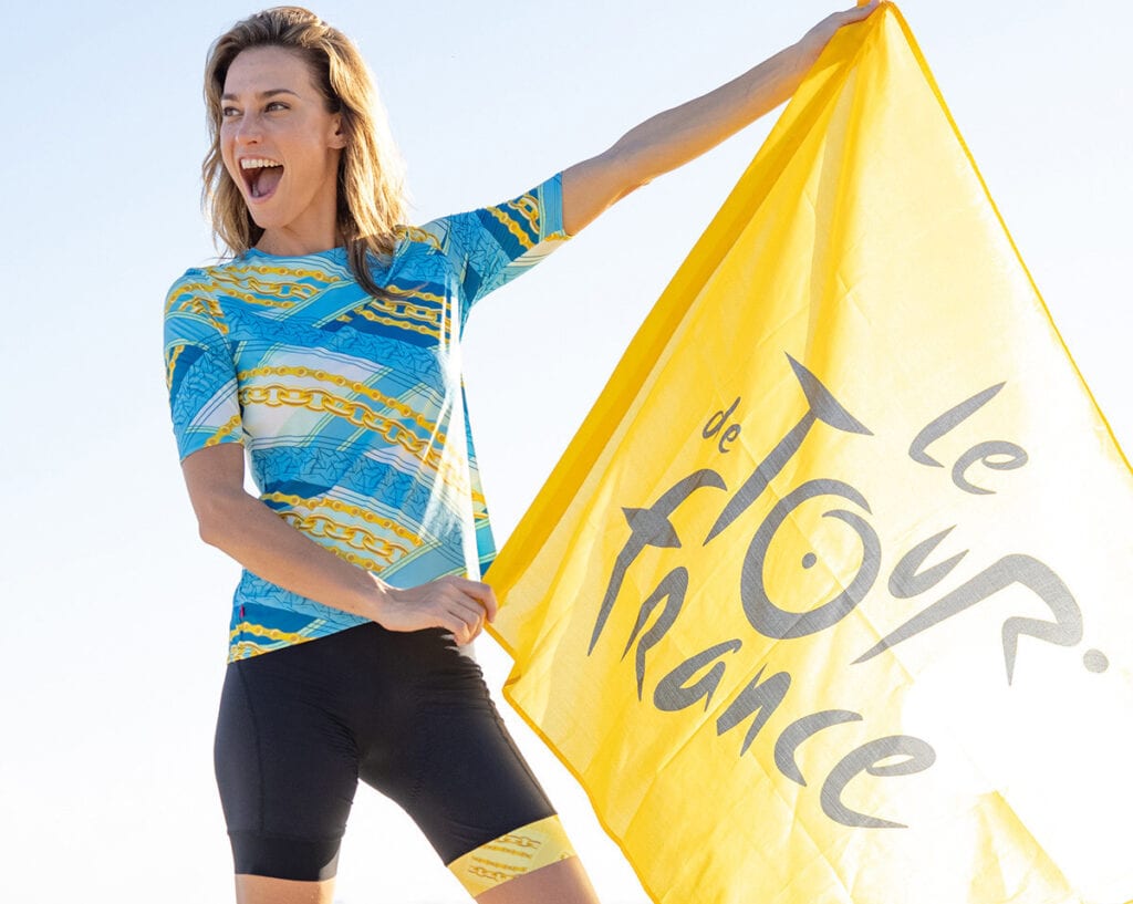 Model wearin g Terry Soleil Short Sleeve Cycling Jersey, holding tour de France flag