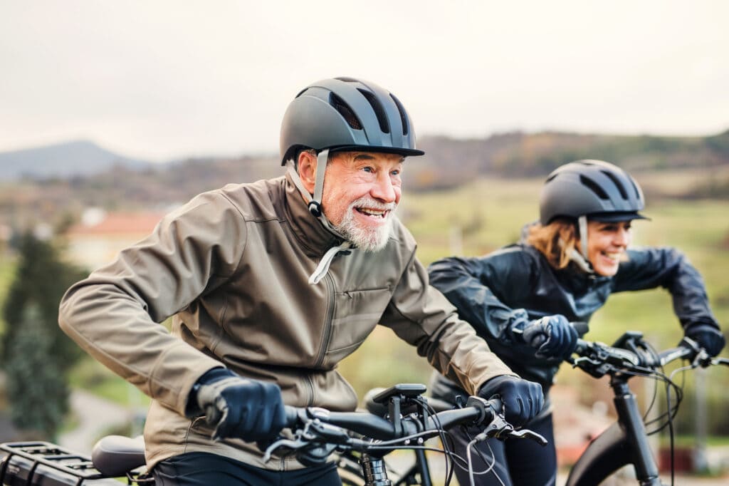 Senior couple racing playfully while riding ebikes in the countryside.