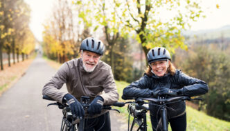 A senior couple pausing while riding ebikes along a wooded road