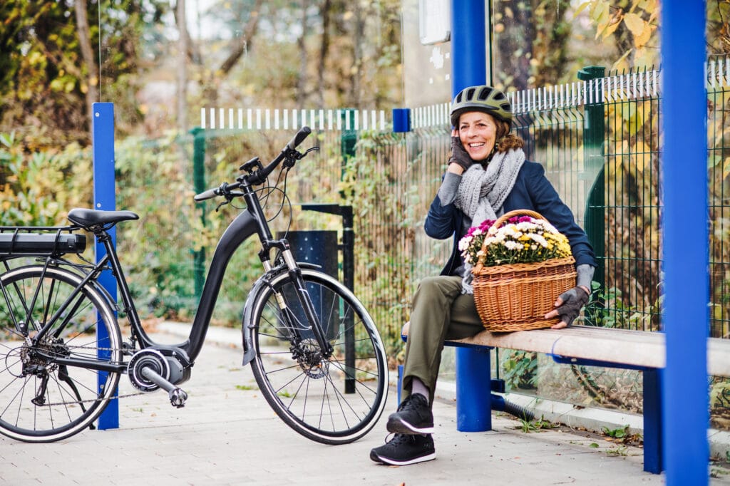 A woman sitting on a bench next to her ebike, pausing during a shopping trip.